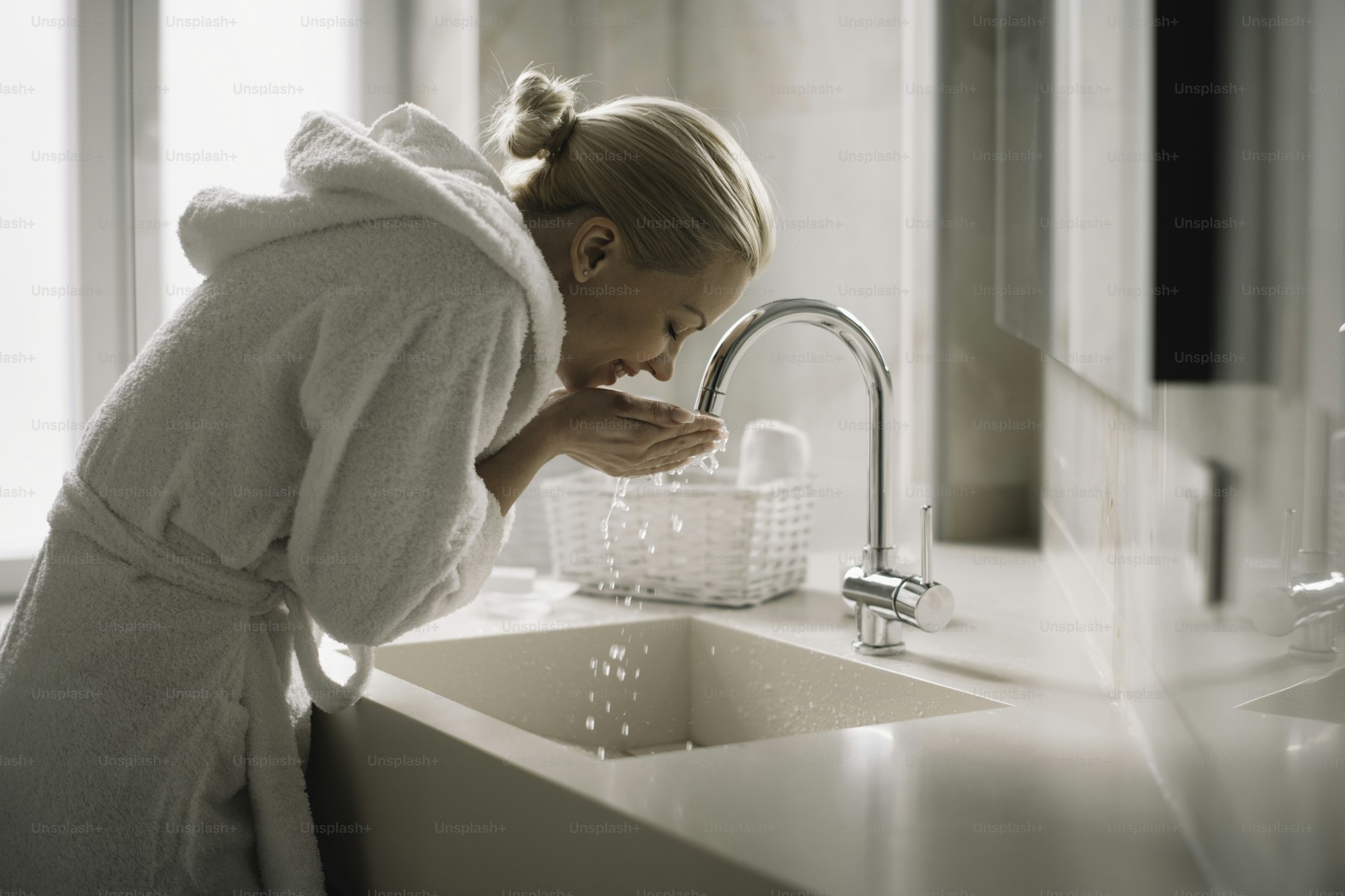 Person rinsing mouth, eyes closed, minimal bathroom setting